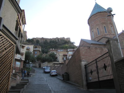 Une rue du centre-ville avec, au fond, la forteresse Narikala.